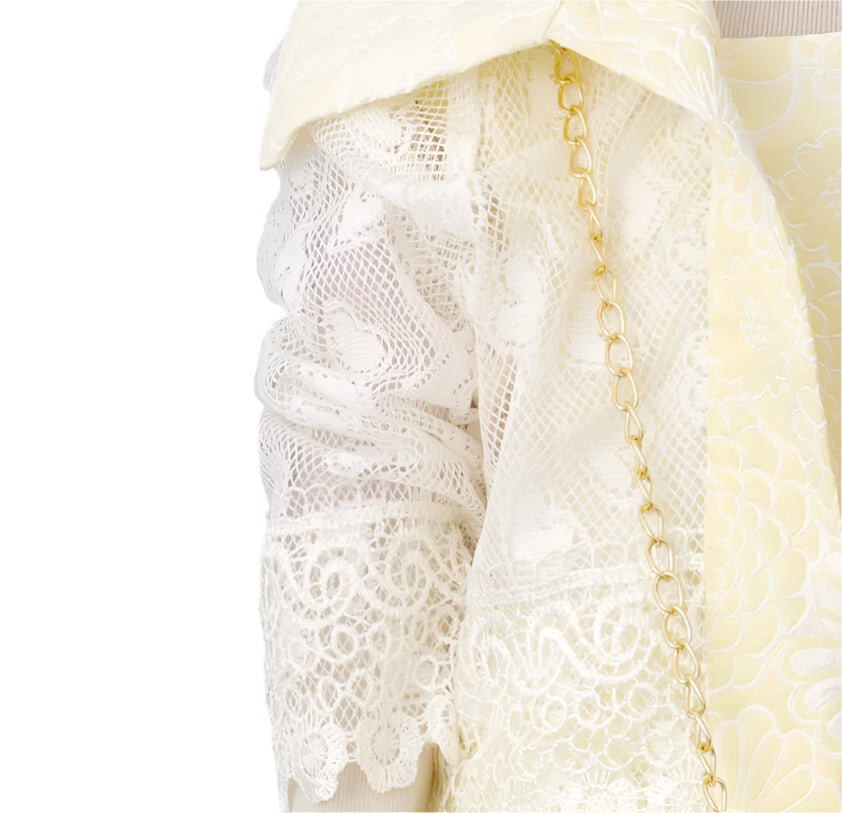 Close-up of a white lace garment with a gold chain on a gray background